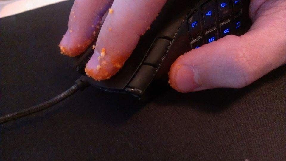 Someone using a gaming mouse with Cheetos all over his fingers.