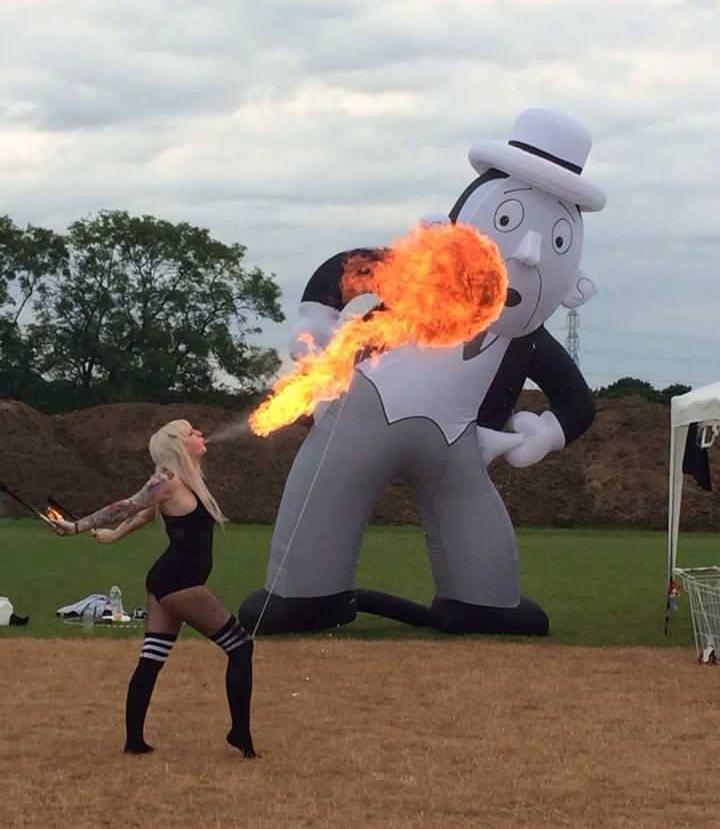 Inflatable butler that looks like he is reacting to show girl blowing balls of fire into the air.