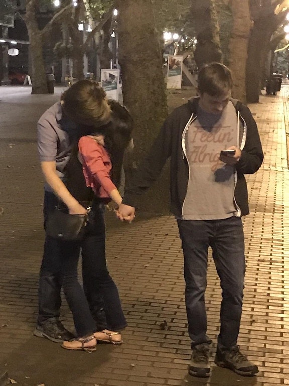 Cringe photo of man on his phone walking with girl in hand as she makes out with 3rd man while he robs her purse.