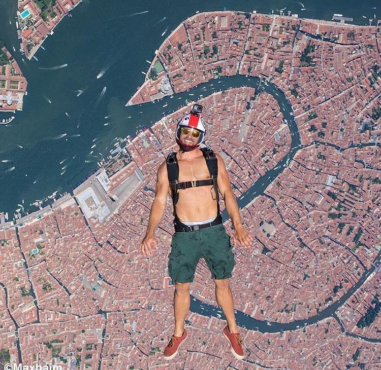 cool picture of man skydiving over Venice with no shirt on