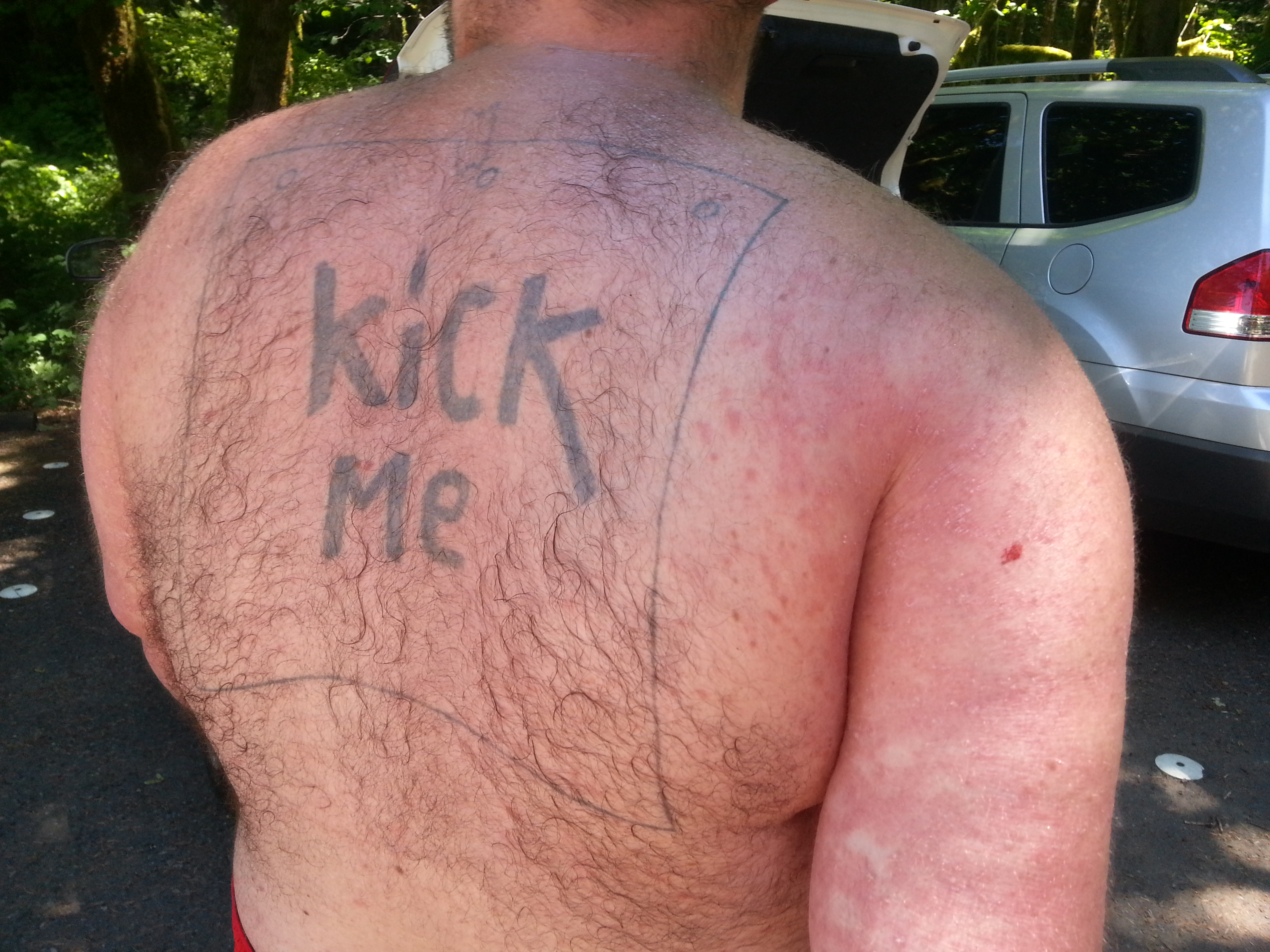 KICK ME tattoo on a man's back