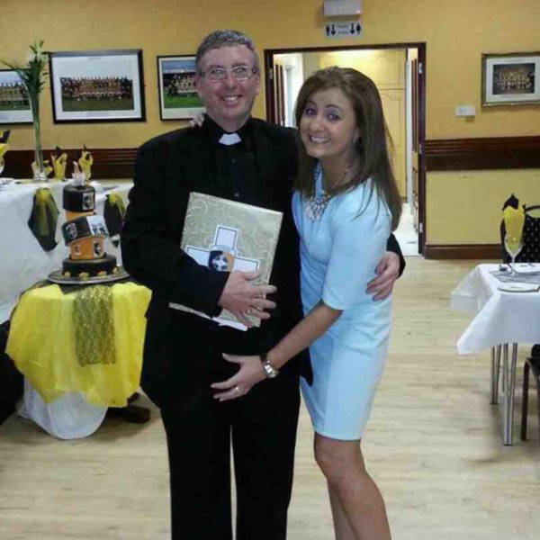 Awkward photo of priest and a young girl with her hand looking like it is in the wrong place.