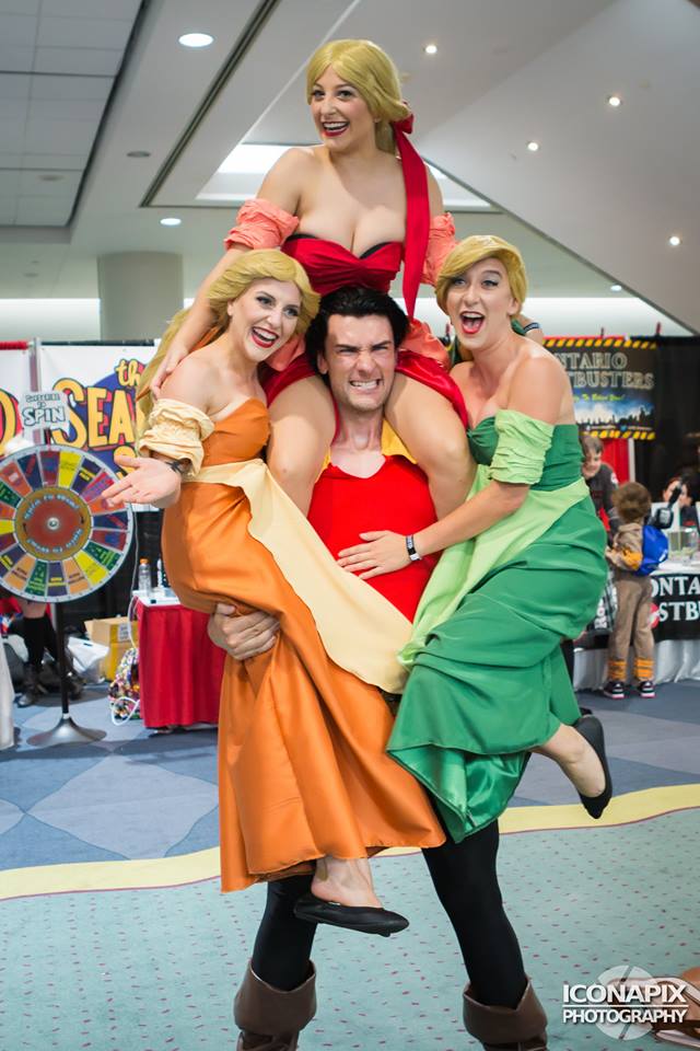 Funny picture of man holding up 3 women at a cosplay convention, with all of them in costume