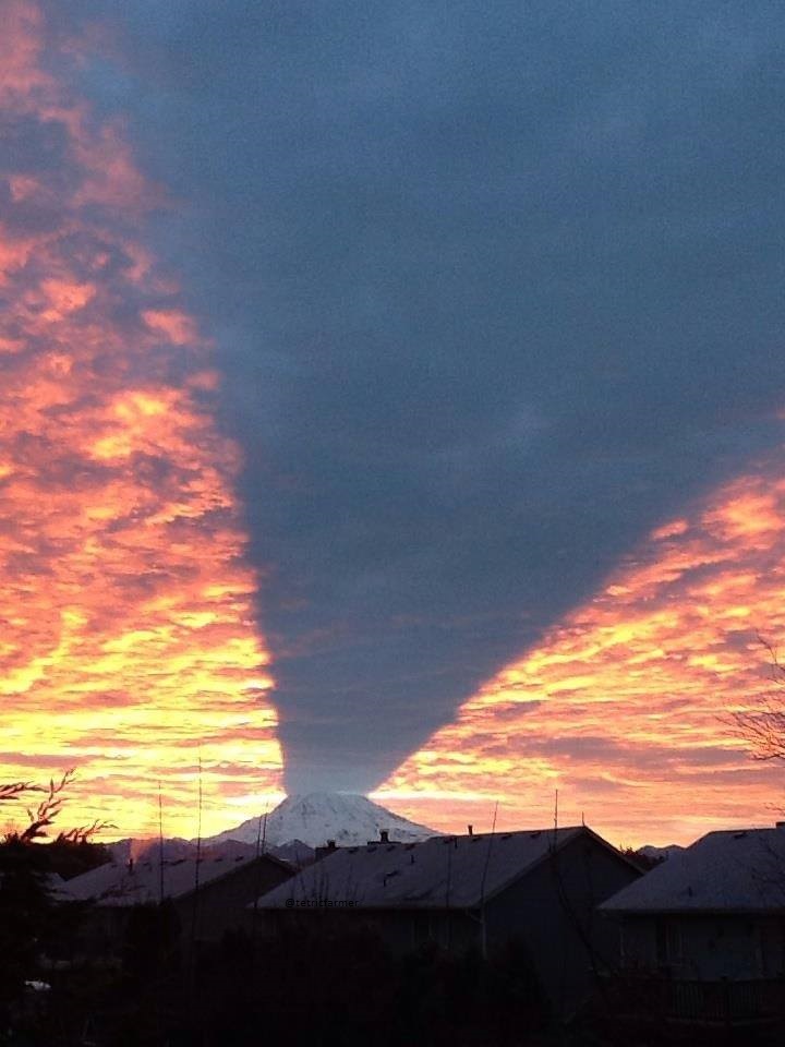 Cool pic of a mountain casting a shadow on the sky.