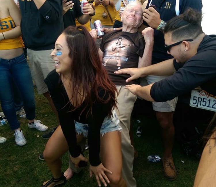Old man at a concert enjoying a girl twerking on him