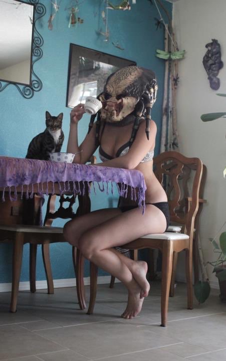 Woman in a Predator mask enjoying her morning coffee
