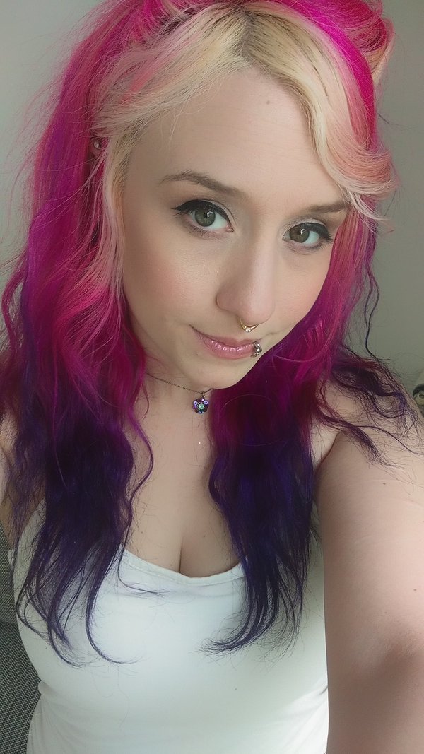 Selfie of pornstar Proxy Paige wearing a white tank top, with hair that turns from pink to Purple, a septum piercing, nose piercing and a necklace.