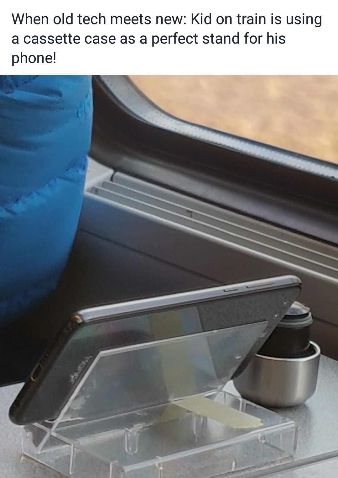 angle - When old tech meets new Kid on train is using a cassette case as a perfect stand for his phone!