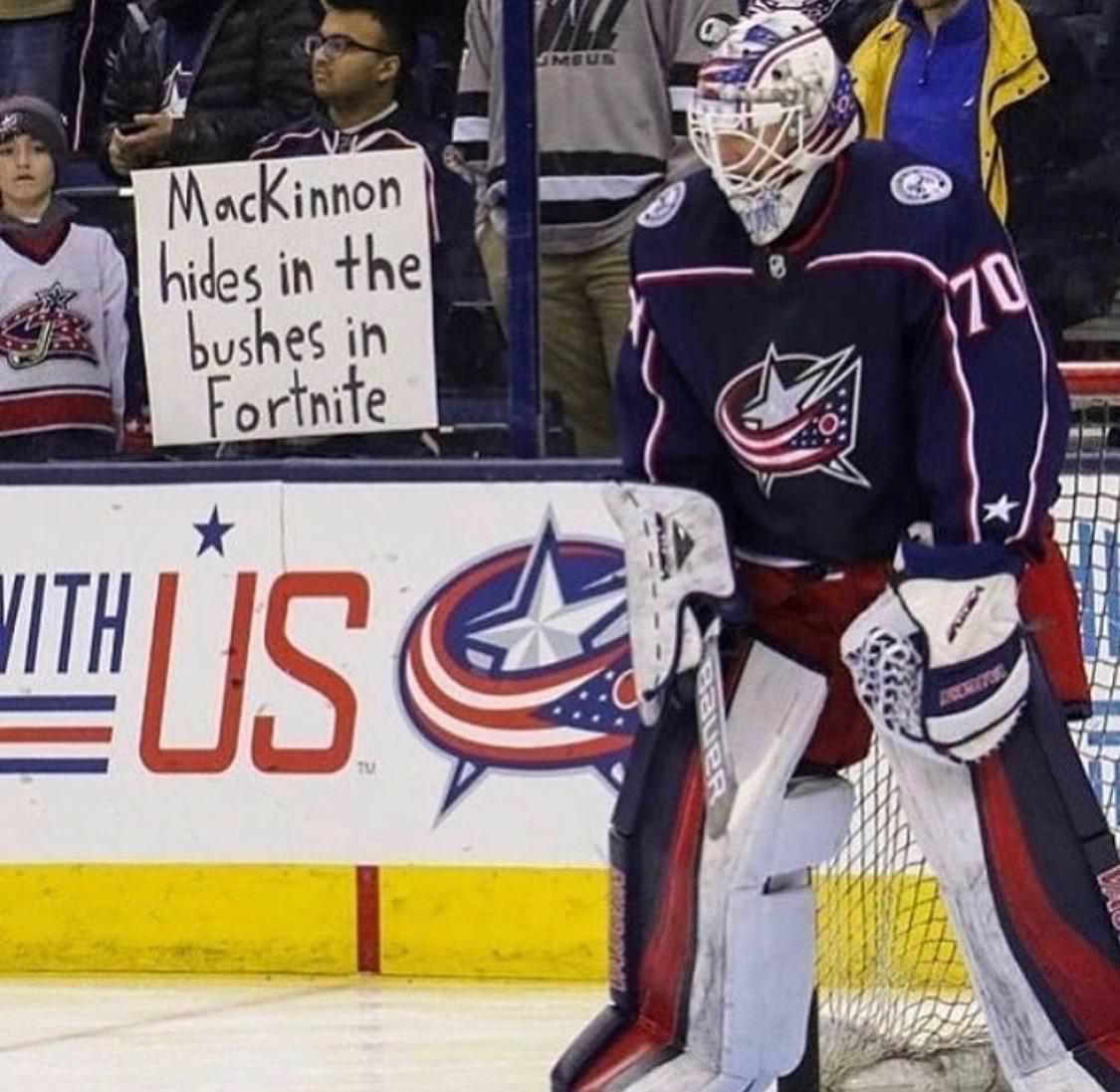 funny picture of man holding up sign accusing hockey player of hiding in the bushes in the video game fortnite