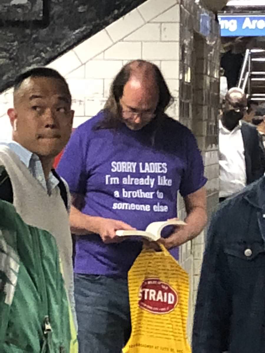 Man with bald head but long on the sides has a t-shirt that says sorry ladies, I am already like a brother to someone else