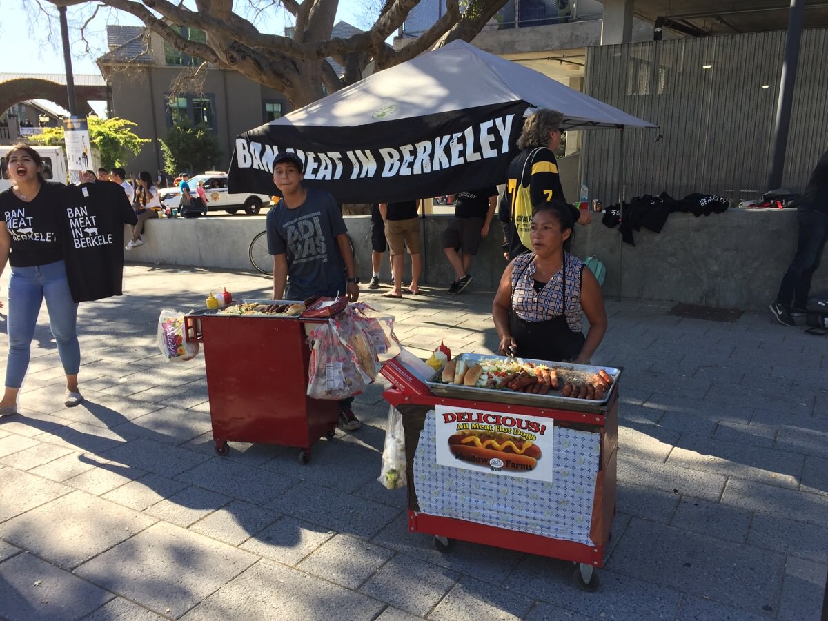 hispanic mother and son team serving hot dogs right opposite a vegan protest
