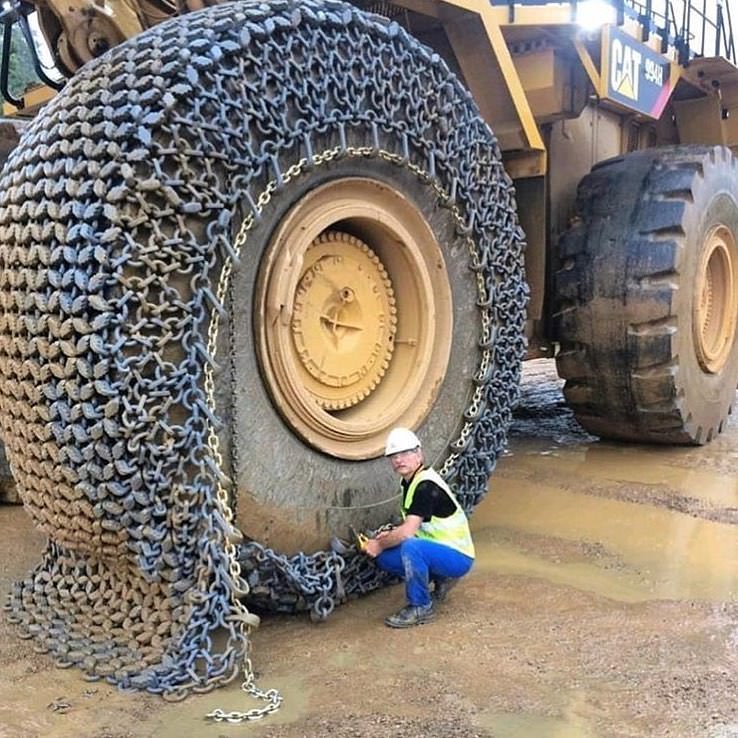 man putting massive tire chains on a front loader