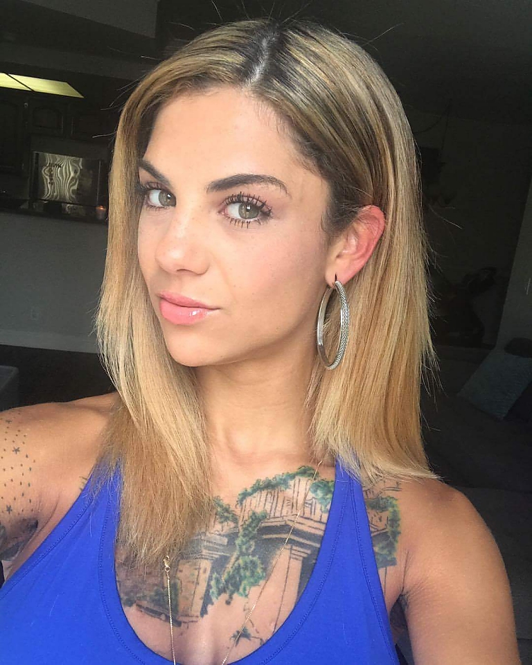 Bonnie Rotten with a blue top displaying her tattoos