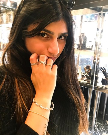 Mia Khalifa wearing jewelry and holding it up to her face.
