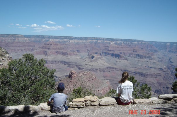 Two people sitting on the edge of the Grand Canyon