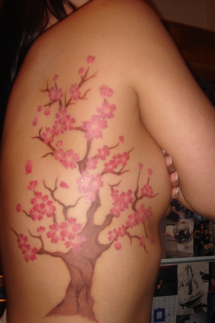 Another beautiful woman with a tree of flowers tattoo on her right side.