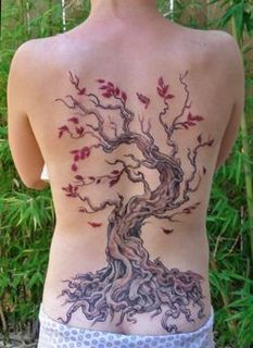 A tattoo of a tree with blosoming flowers on the back of a woman