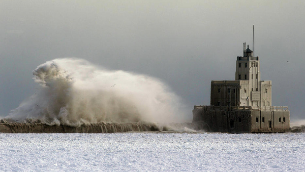 High waves pound along a break wall near a lighthouse in Lake Michigan.