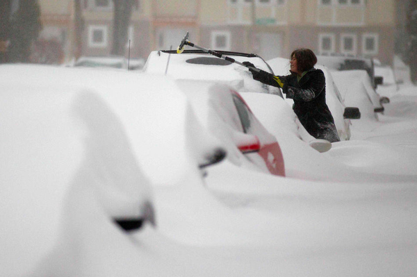 Cars are buried as a woman tries to clear her windshield in Milwaukee.