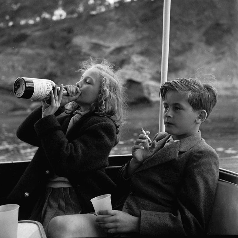 Two young children drink and smoke on a yacht