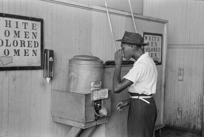 A black man drinking from the "Colored" water cooler in Oklahoma City in July, 1939