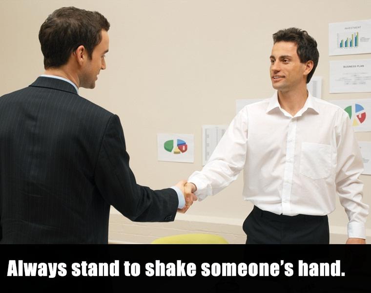 2 white people shaking hands - Always stand to shake someone's hand.