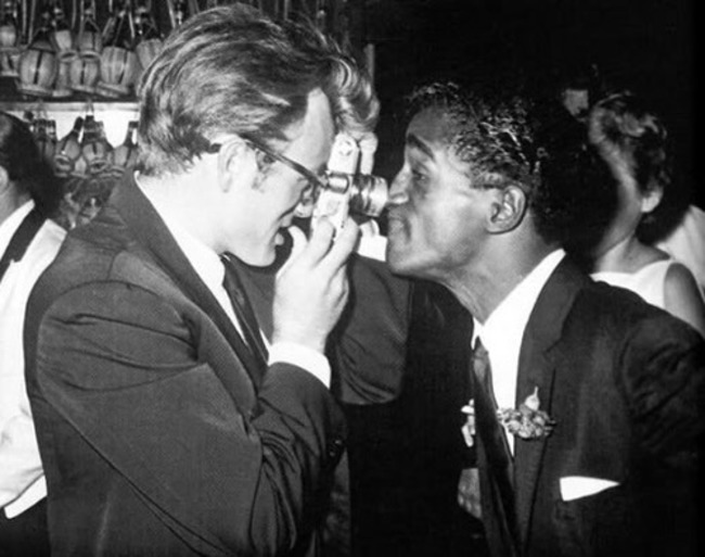Sammy Davis Jr. nosing up to actor James Dean's camera.