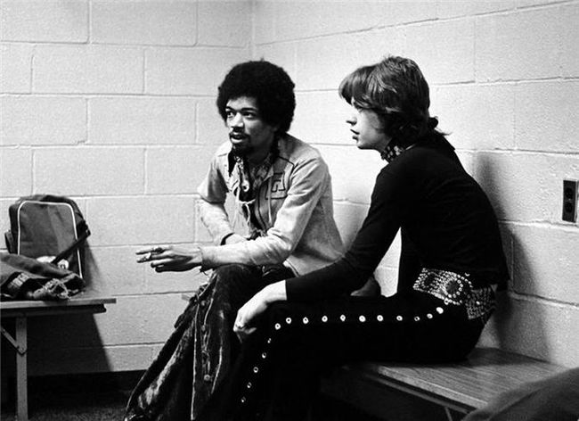Jimi Hendrix and Mic Jagger sharing a cigarette backstage.