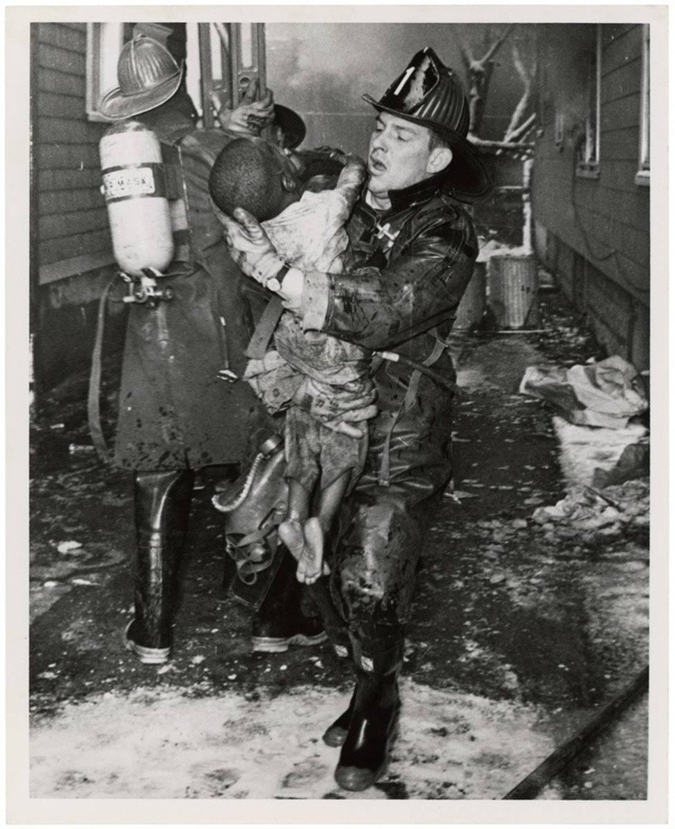 A fire fighter pulls a young boy from a fire.