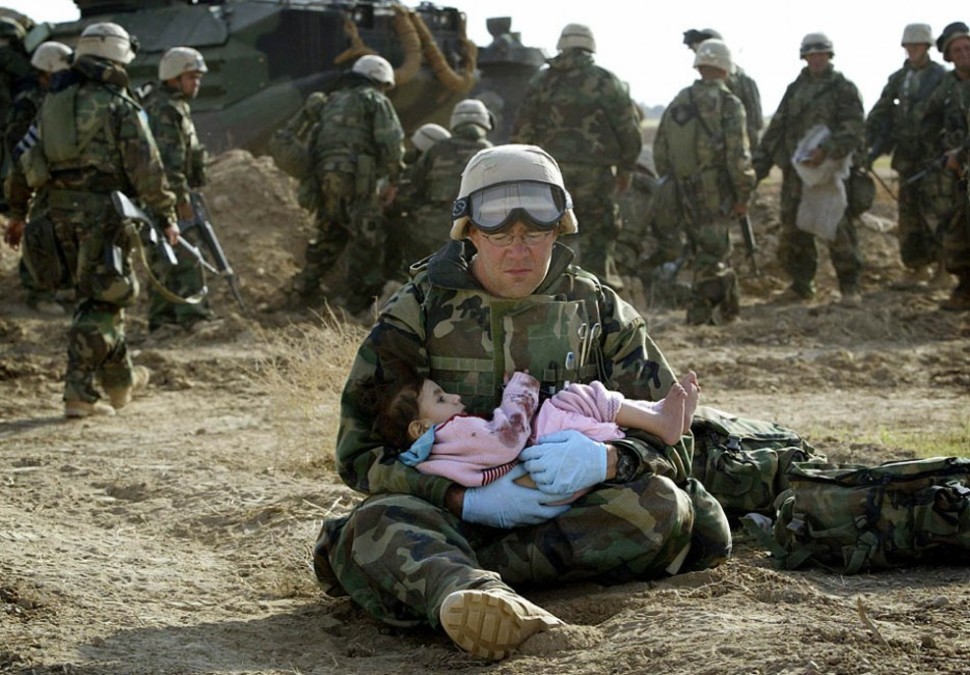 U.S. Navy Hospital Corpsman HM1 Richard Barnett holds a child after she was separated from her family during a fire fight.