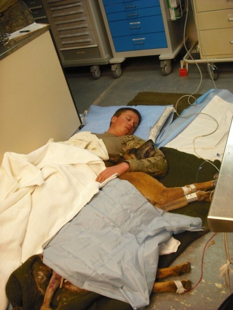 Petty Officer Ryan Lee and Valdo snuggle on a hospital floor after a lucky escape.