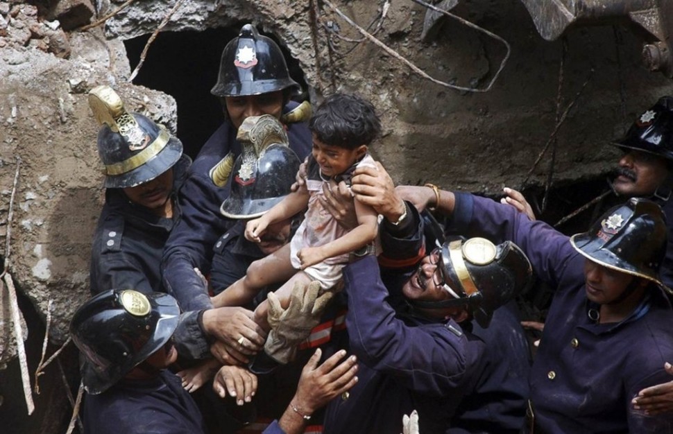 Rescue workers carry a child who was rescued from the rubble at the site of a collapsed residential building in Mumbai.