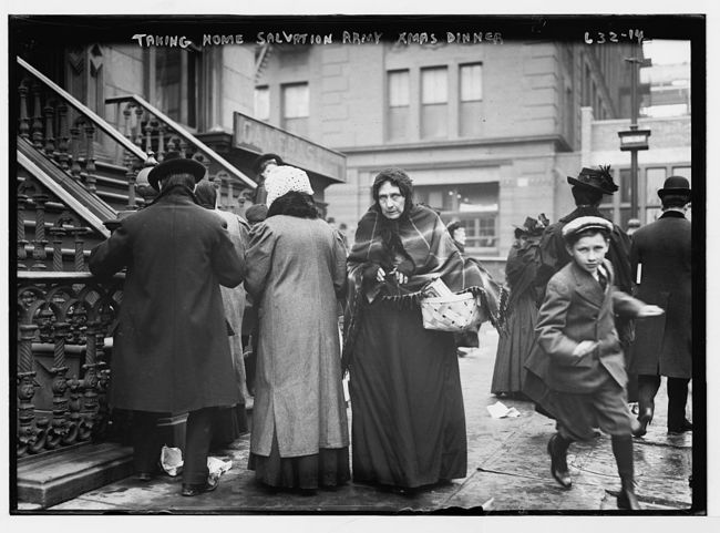 A woman takes home a Christmas dinner in a basket, provided by the Salvation Army to the poor. 1910