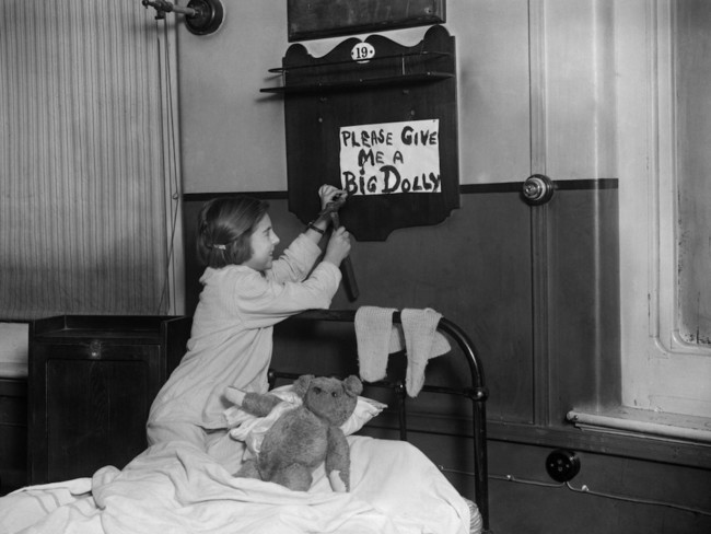 A girl hammers up a request to Father Christmas above her bed at the Brecknock School for Blind Children.  1925