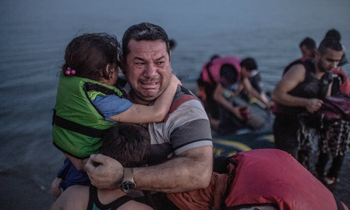 Safe landing: Laith Majid from Deir Ezzor in Syria, holding his son and daughter, breaks out in tears of joy after arriving via a flimsy inflatable boat crammed with about 15 men, women and children on the shore of the island of Kos in Greece.