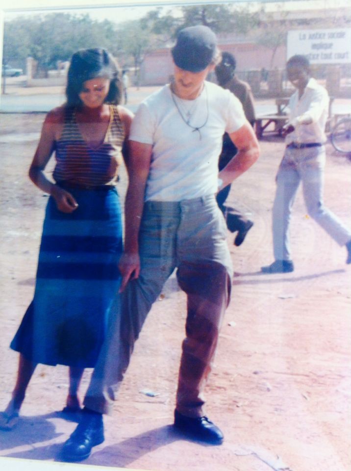 A picture of a 20-something couple in Kenya (1988). The man is teaching the woman how to dance, while two local men laugh at his.