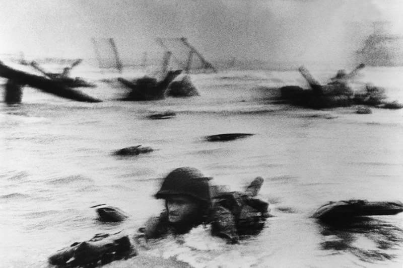 Robert Capa captures a soldier emerging from the waters on D-Day.