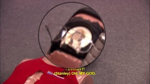 Dwight puts his glasses on the CPR dummy while he wears it's face