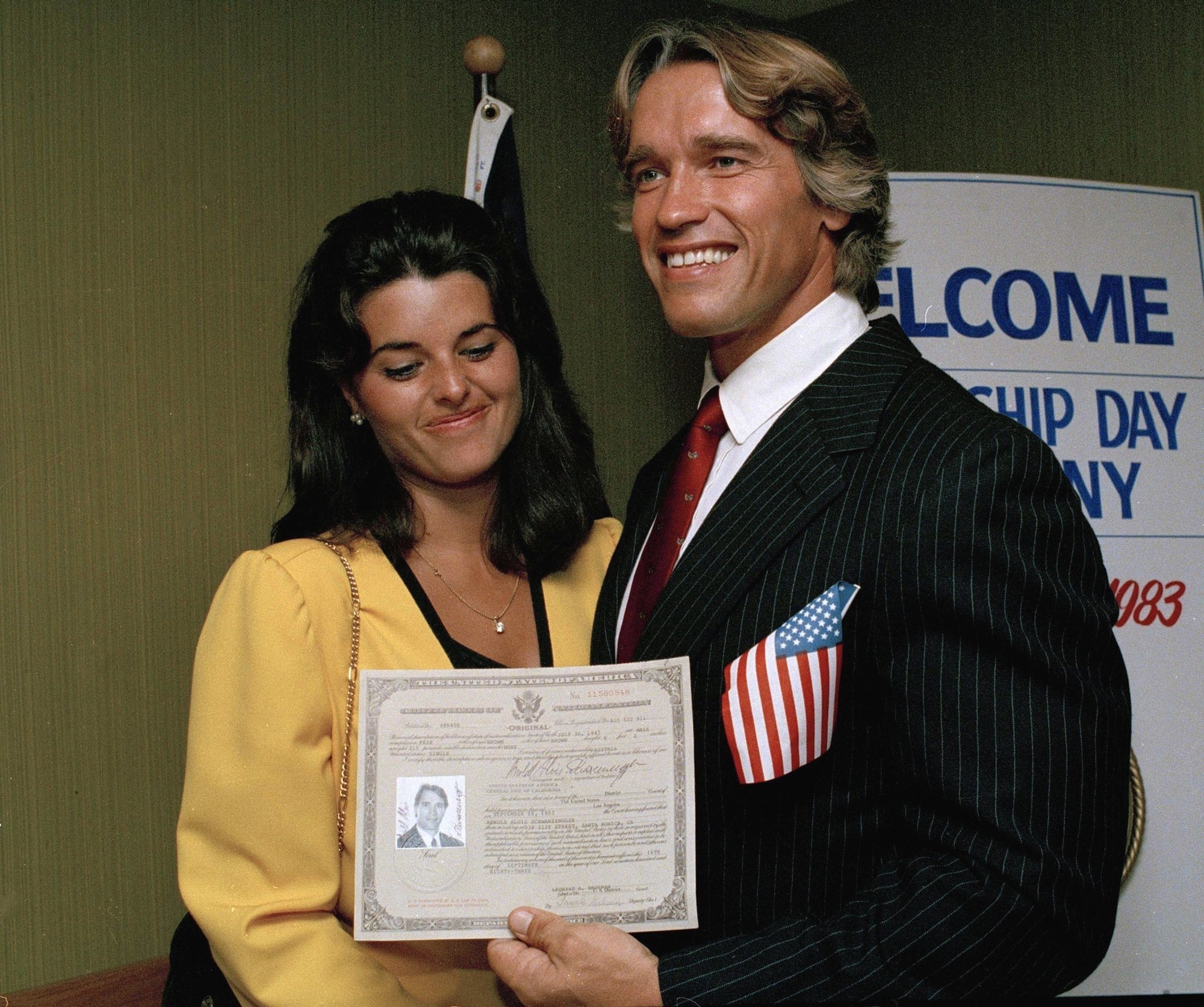 Arnold Schwarzenegger proudly shows off his US citizenship documents in 1983.