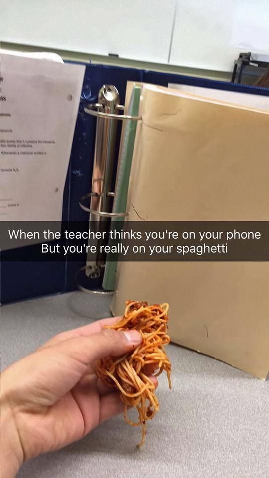 Snapchat of someone acting like they are on their phone in class but they are actually just holding spaghetti.
