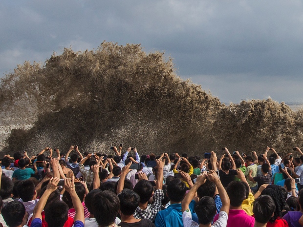 Visitors take pictures of giant tidal waves crashing against the shore in Hangzhou, Zhejiang province, China, in September.