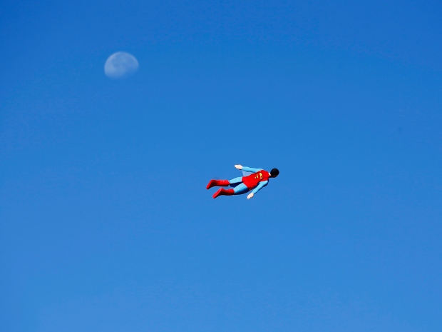 A radio-controlled Superman, flown by designer Otto Dieffenbach. The model, passing in front of the moon during a test flight in San Diego, is one of several superhero-shaped aircraft Dieffenbach has created.