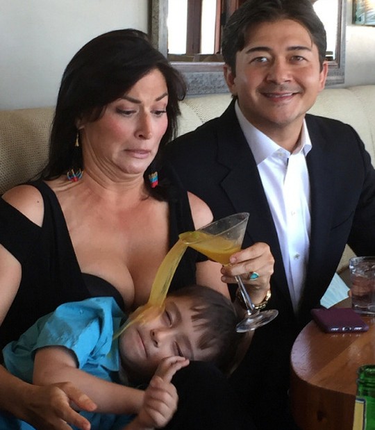 Funny picture of woman accidentally spilling her cocktail drink by accident on her sleeping child.