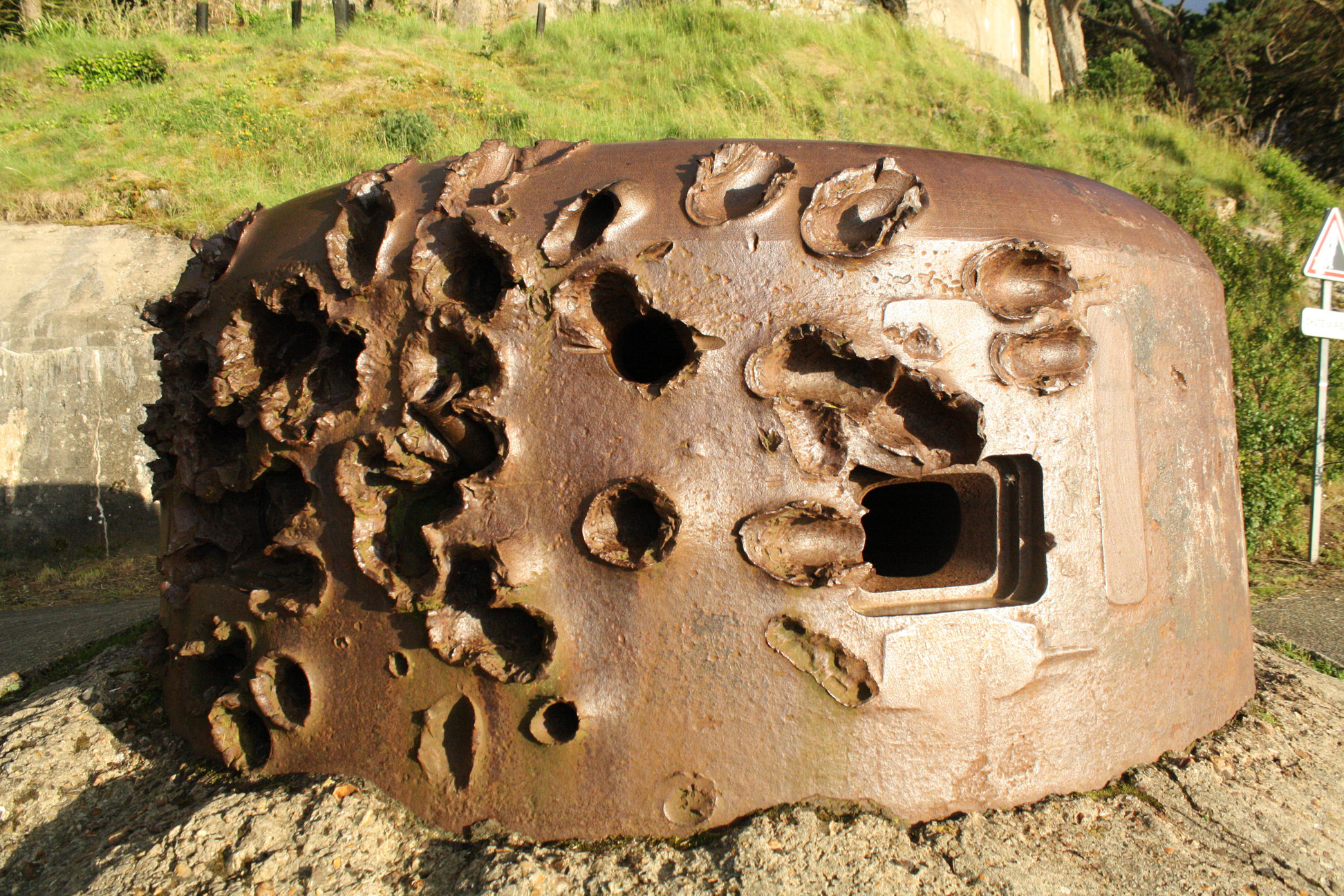 A German gun turret from WWII in France that clearly received some heavy attacking fire.