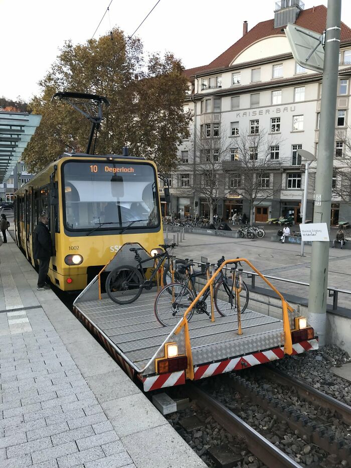 This light rail train has a trailer for bikes on the front of it.