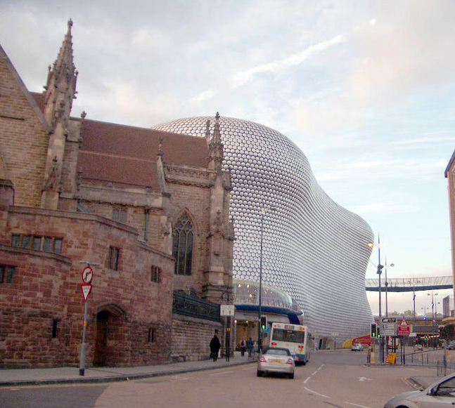 A 16th century Gothic cathedral stands in front of a 21st century Blobitecture complex owned by Selfridges  Co in Birmingham, England.