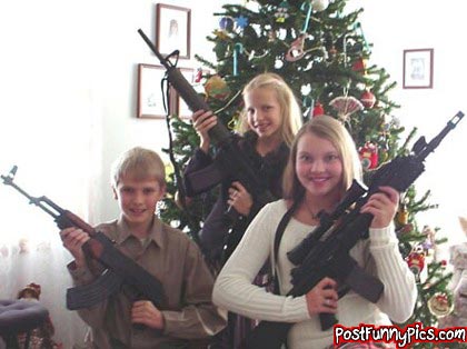 funny picture of kids in front of their christmas tree and they are all holding assault rifles