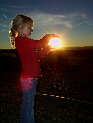 cute kid holding the sun in the palm of her hand