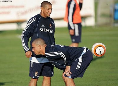 A soccer player hitting a ball with his butt with his face next to a guy's own ball.