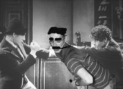 Chico fights Groucho while Harpo holds him.